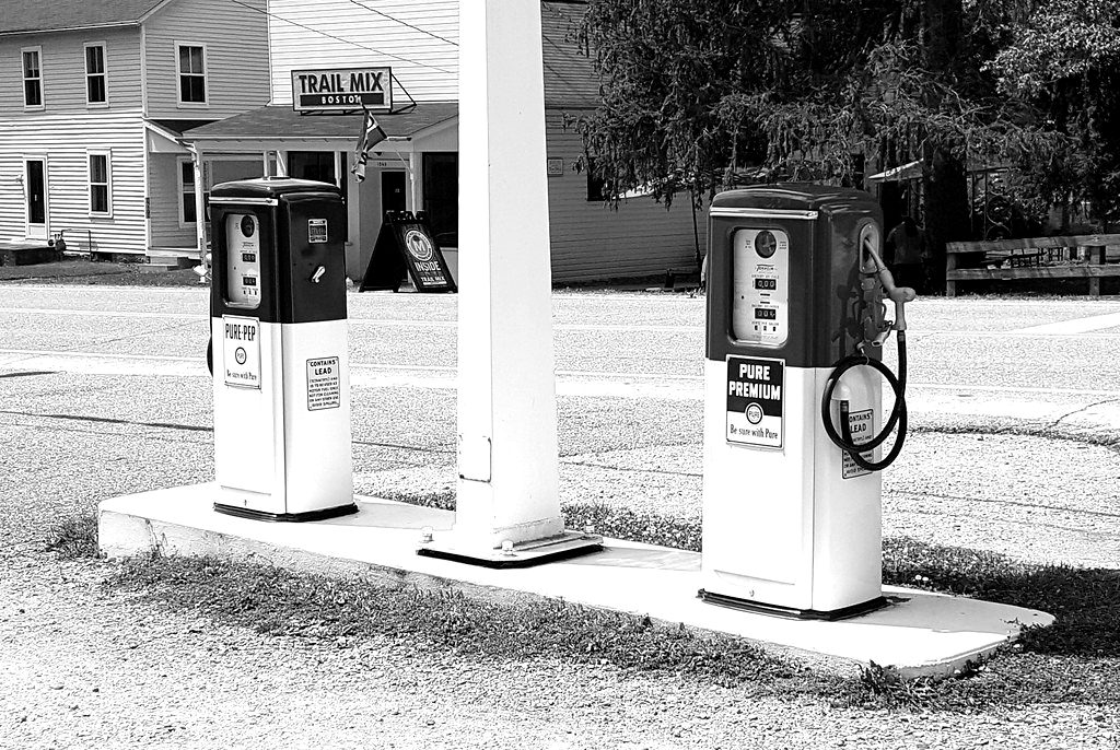 Two vintage petrol pumps outside a small shop