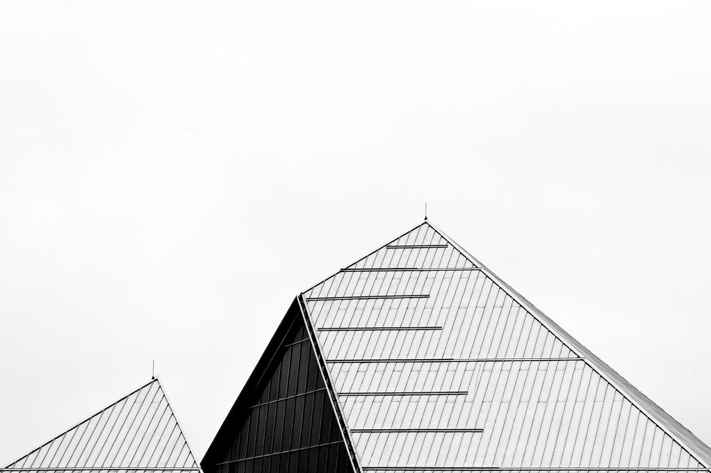 The sloped edge of a glass pyramid roof against a pale sky