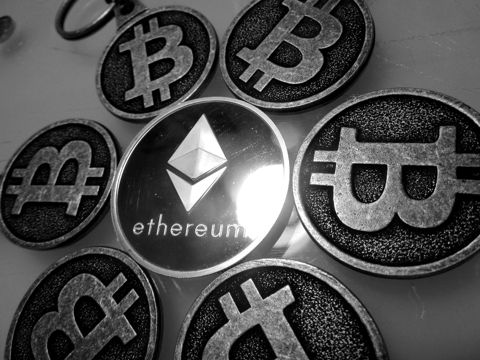 An Ethereum commemorative coin surrounded by Bitcoin coins
