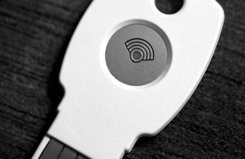 A white USB hardware security key on a wooden desk