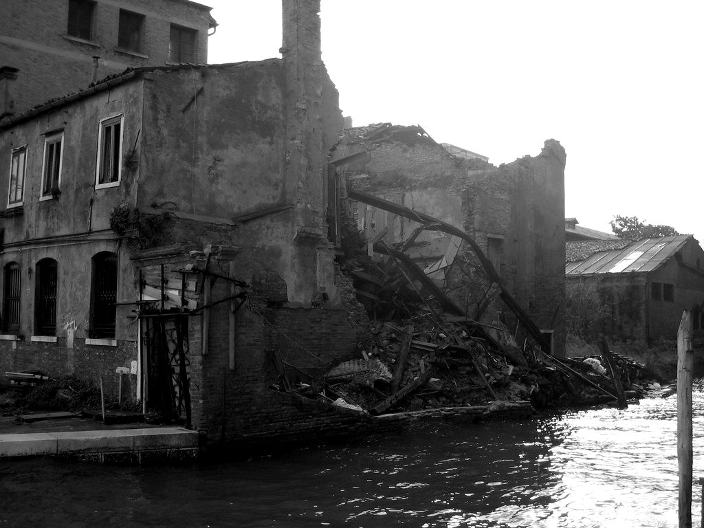 A partly collapsed brick building beside a canal