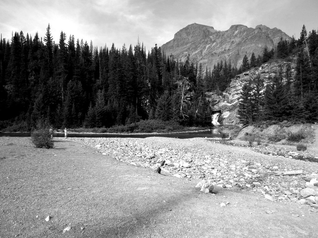 A nearly dry riverbed below mountains