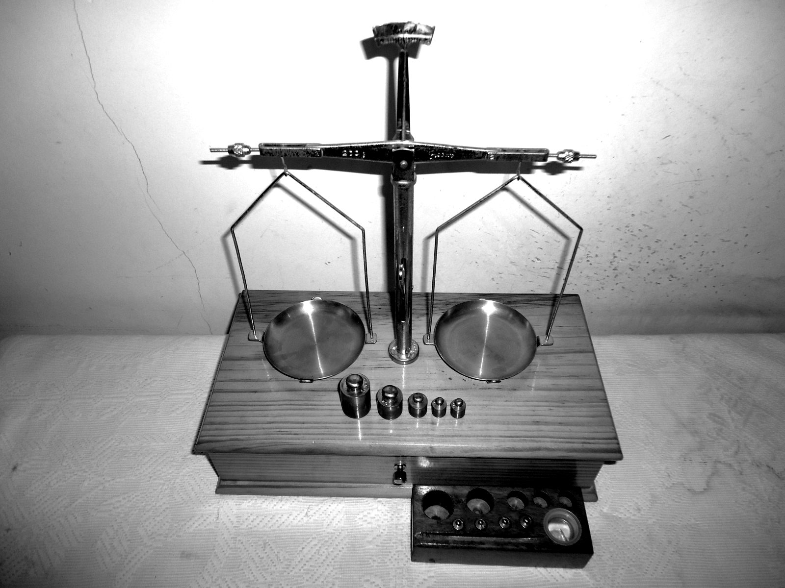 A laboratory balance with brass weights on a wooden base