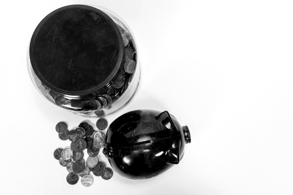A coin jar, scattered pennies and a red piggy bank
