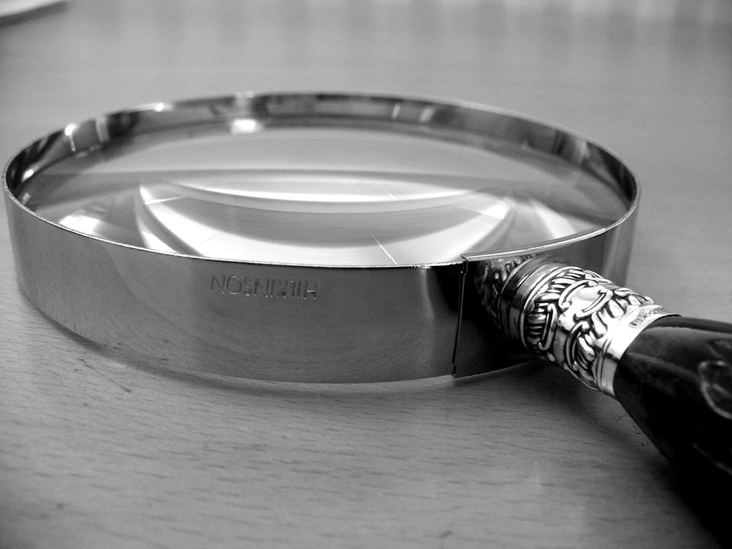 A silver magnifying glass on a polished desk
