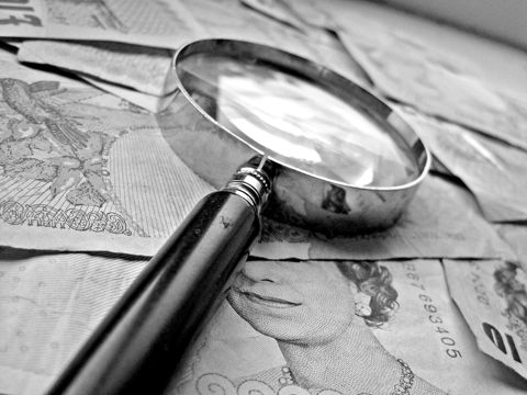 A magnifying glass resting on a spread of banknotes