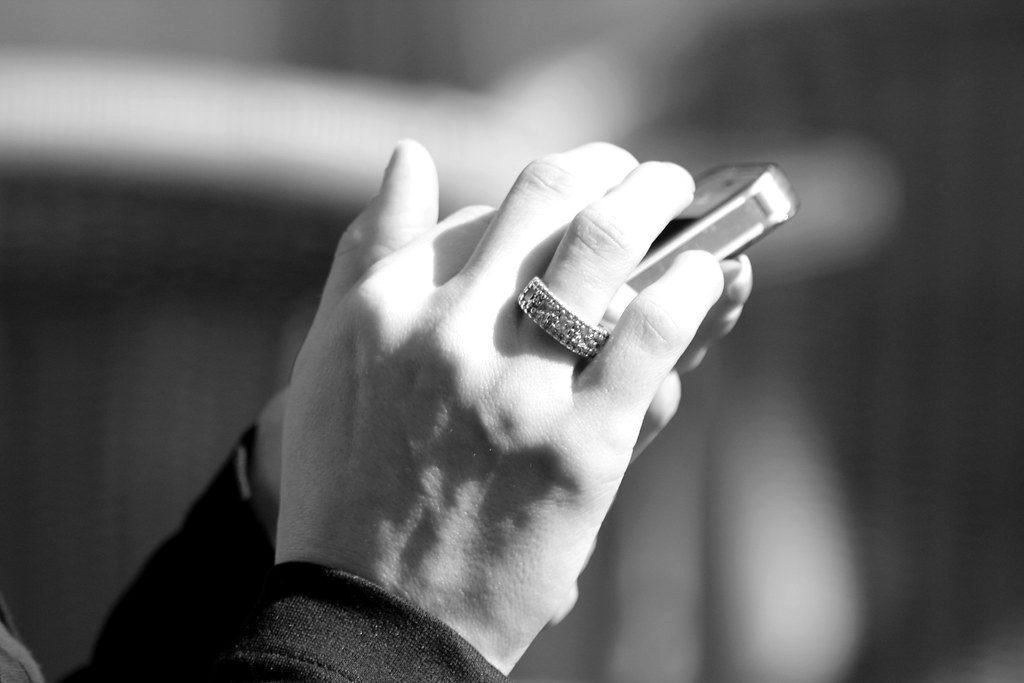 A hand with rings holding a smartphone