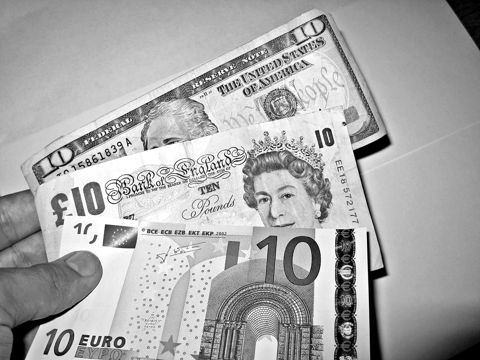 Dollar, pound and euro banknotes held in a hand