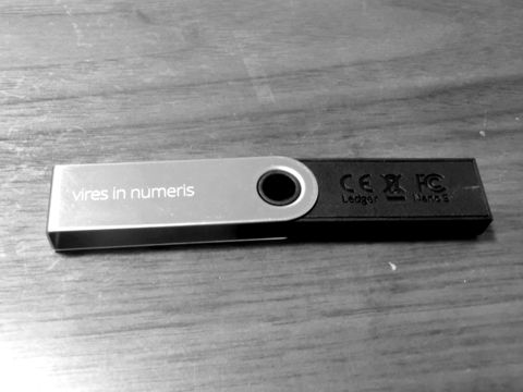 A USB-stick hardware wallet lying on a wooden table
